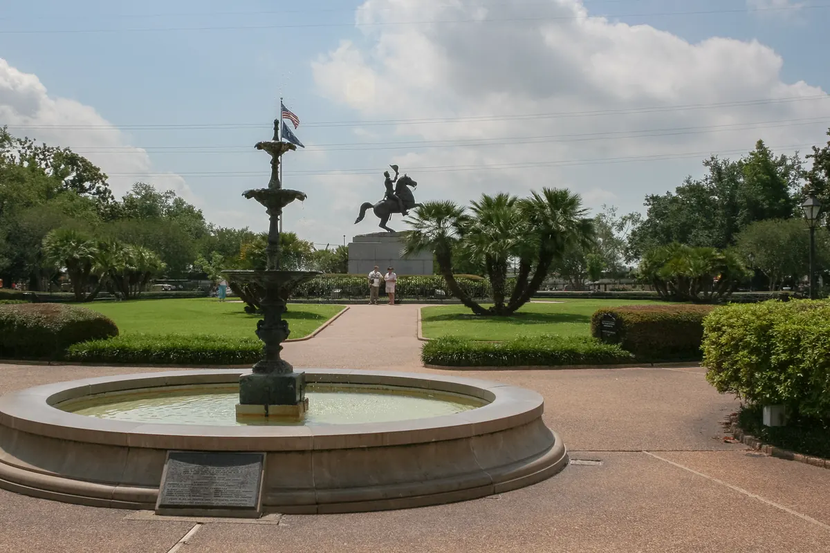 La fontana e la statua di Andrew Jackson a cavallo in Jackson Square, New Orleans, tra palme e siepi potate sotto un cielo nuvoloso